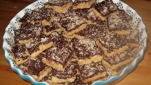 Bowl of square cookies with dark chocolate topping and light sprinkles.