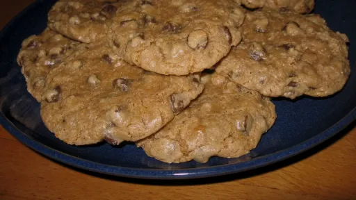 Freshly baked chocolate chip cookies piled on a blue plate.