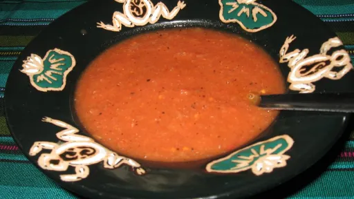 Dark green frog bowl with red fire-roasted salsa and a spoon.