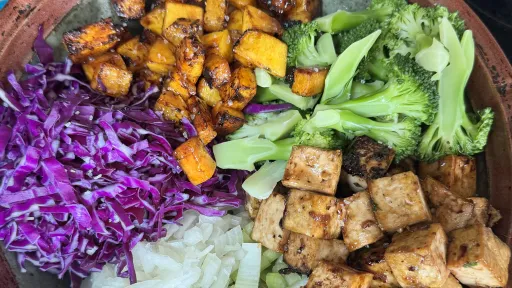 Colorful bowl with roasted squash, tofu, broccoli, red cabbage, onion, and celery.