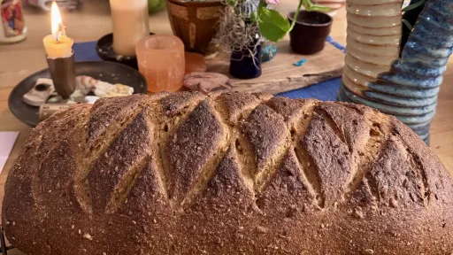 Freshly baked whole grain bread with a diamond pattern, on a table with candles and flowers.