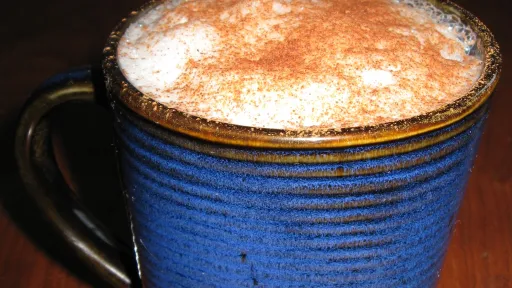 Blue ribbed mug with frothy drink topped with cinnamon powder.
