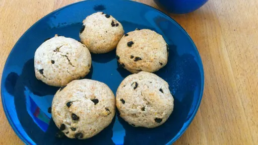A close-up of a person's hand holding a small, round white pill between their thumb and index finger.