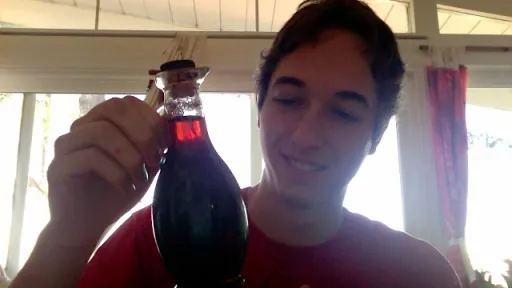 Adam holding a corked bottle of dark vanilla syrup, smiling.
