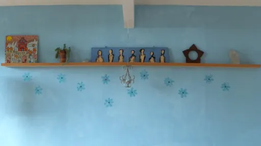 A decorative wooden shelf above a red sofa against a blue wall with flower decals.