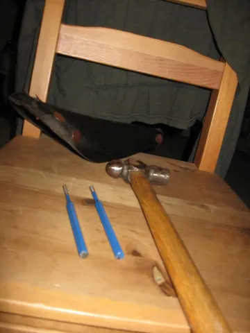 A person's hand holds a small, white, heart-shaped pill that is scored in the middle.