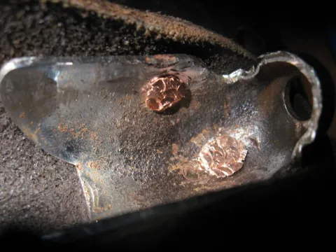A woman with light brown hair, wearing a grey shirt, looks intently at a white document she holds with both hands.