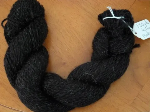 Dark llama yarn skein on a wooden surface.