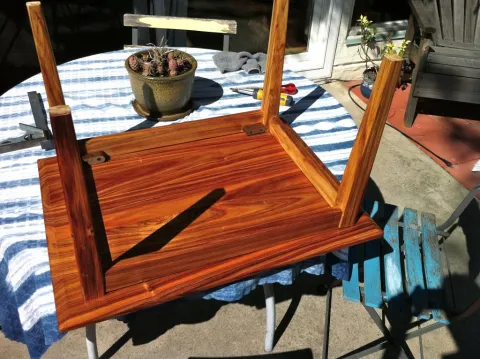 Upside-down wooden table on blue and white striped tablecloth outdoors.