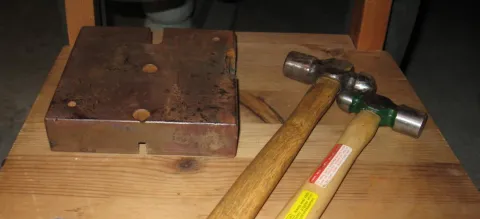 A single, glossy red apple with a short brown stem on a white background.